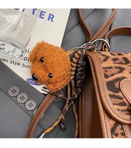 Brown curly teddy bear plush charm on leopard print shoulder bag with woven strap