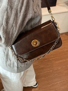 Vintage dark brown crossbody bag with gold chain and buckle shown on a female model