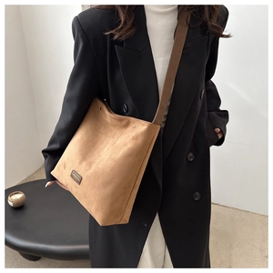 Detail of vintage brown faux suede tote bag with leather tag on black blazer outfit
