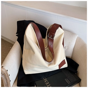 Detail of adjustable reddish-brown leather strap and silver buckle on canvas tote bag