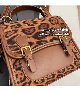 Close-up of leopard print crossbody bag with brown leather trim and gold buckles
