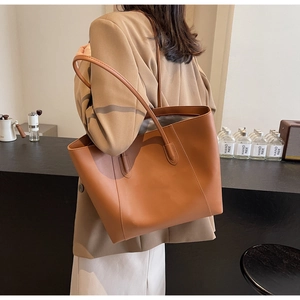 Detailed view of a caramel leather tote bag styled on model in minimalist setting