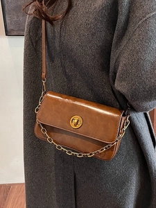 Vintage caramel brown leather crossbody bag with gold chain and circular lock on model