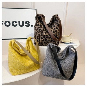 Dettaglio di tre borse tote in peluche con stampa leopardata, gialla e maglia grigia