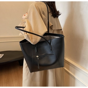 Detailed view of black tote bag with front zipper pocket and long shoulder straps