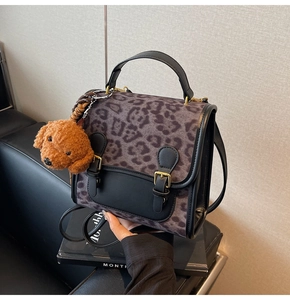 Close-up of leopard print handbag with gold buckles and brown teddy bear charm
