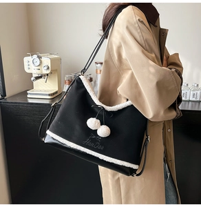 Detail of Korean style black tote bag with white plush trim and fluffy ball charms
