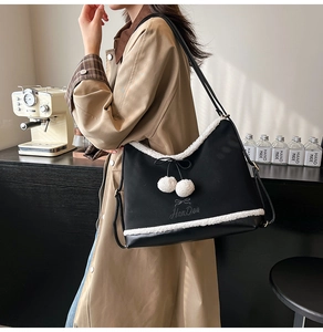 Detail of black faux leather tote with white fleece trim and decorative pom-poms