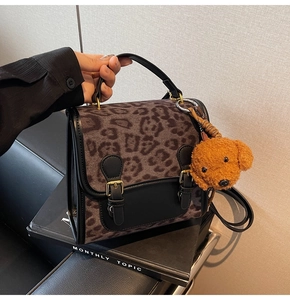 Close-up of leopard print handbag with leather contrast trim and bear charm