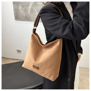 Detailed view of brown matte suede tote bag with leather strap worn by a model