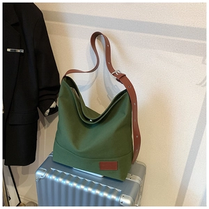 Detail of dark green canvas tote bag with adjustable brown leather strap on luggage