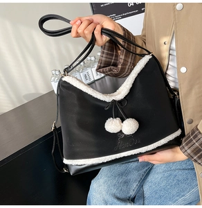 Detail of black leather bag with white faux fur trim and plush pom-pom charms