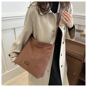 Detail of vintage brown suede tote bag with leather strap and embossed fashion label