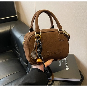 Detalle de bolso de ante marrón con logo MEDEAR y accesorio de raqueta de tenis