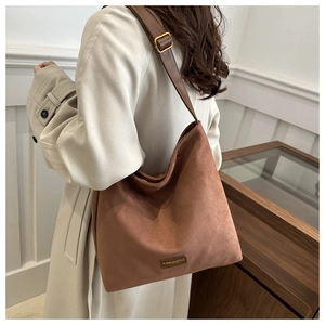 Detail of vintage brown suede tote bag with golden buckle and leather strap on model