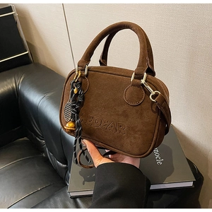 Detalle del bolso Boston de ante marrón con logo EDEAR grabado y adornos de temática de tenis