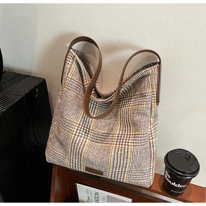 Detail of classic houndstooth pattern fabric and premium leather handles on a tote bag