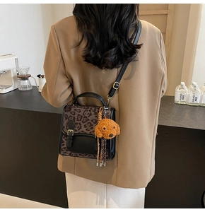 Detail of leopard print crossbody bag with black leather flap and cute plush dog pendant