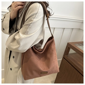 Detail of a brown suede hobo bag with a gold buckle and adjustable shoulder strap