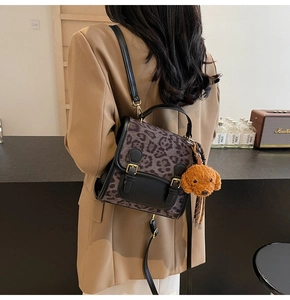 Macro shot of stylish leopard print backpack with gold buckles and plush charm