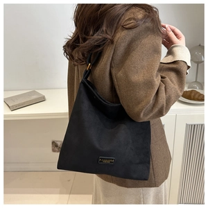 Close-up of the matte black suede texture and brand tag on this vintage tote bag