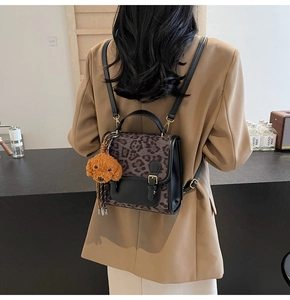 Close-up of leopard print backpack with black leather flap and cute dog charm detail
