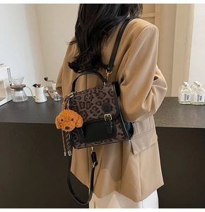 Detail of leopard print backpack with black leather flap and cute plush dog charm