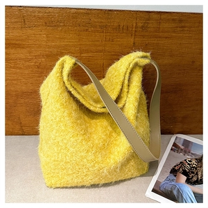 Dettaglio della trama in peluche giallo di una borsa a tracolla con tracolla in pelle