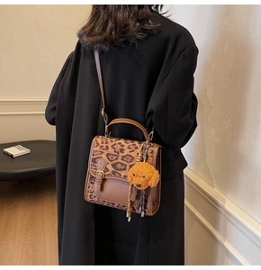 Detail of leopard print patchwork crossbody bag with brown leather and puppy charm