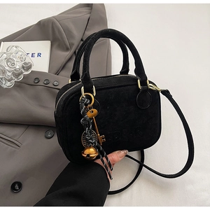 Detalle de bolso negro mate con herrajes dorados vintage y colgante de campana