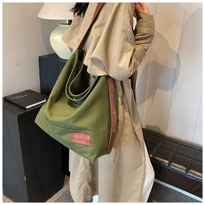 Detail of green canvas hobo bag with brown leather strap worn over the shoulder