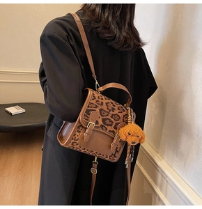 Detail shot of leopard print crossbody bag with plush dog charm on a female model