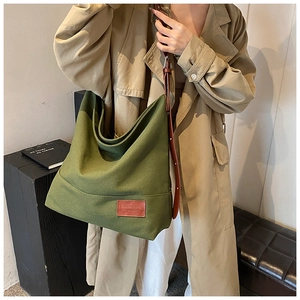 Detail showing high-capacity canvas bag with green fabric and adjustable leather strap