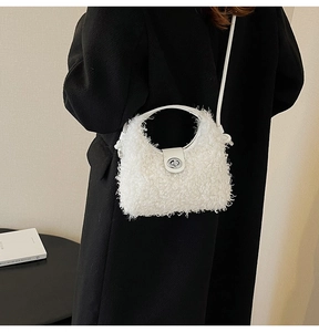 Close-up of white plush handbag with silver metal clasp against a dark coat