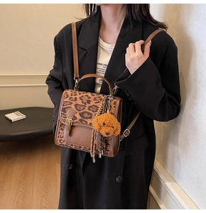 Detail of leopard print handbag with contrast stitching and plush dog charm