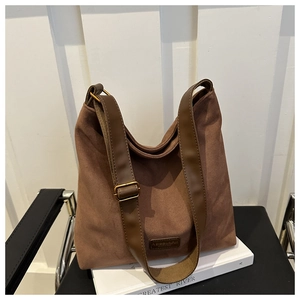 Macro detail of brown suede hobo bag with leather strap and fashion label on chair