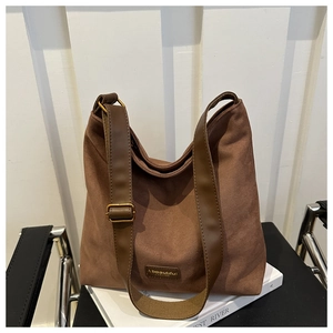 Detail of matte brown tote bag with adjustable shoulder strap and fashion label on a chair
