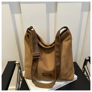 Detail of brown suede bucket bag featuring adjustable leather strap and golden buckle