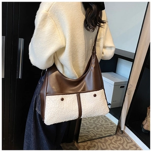 Detail of contrast stitch tote bag featuring brown leather and white faux shearling texture
