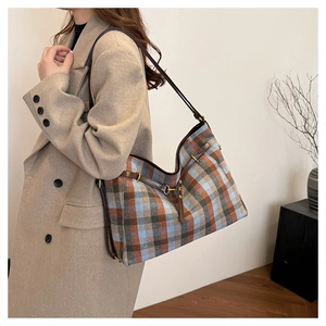 Détail du sac cabas à carreaux avec lanières en cuir et boucles métalliques sur un mannequin