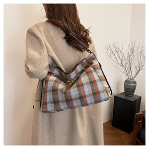 Détail d'un grand sac cabas à carreaux bleus avec sangle latérale en cuir marron vintage