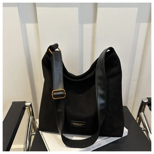 Detail of black frosted tote bag featuring gold hardware and adjustable wide leather strap