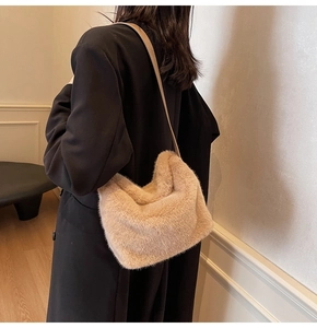 Detail einer weichen Plüsch-Schultertasche in Beige zu einem minimalistischen schwarzen Mantel