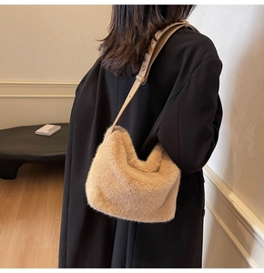 Detail der khakifarbenen Plüsch-Schultertasche mit braunem Lederriemen auf schwarzem Mantel