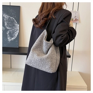 Dettaglio della borsa tote in maglia grigia con trama in tweed su cappotto nero