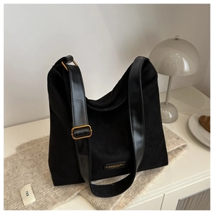 Close-up of black canvas hobo bag with leather strap and vintage gold buckle on a desk