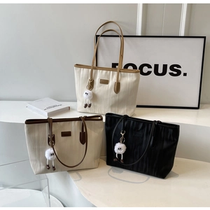 Detailed view of textured tote bags in black and beige with plush charm accessories