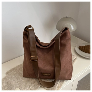 Detail of vintage brown frosted leather tote bag with brand patch on white desk