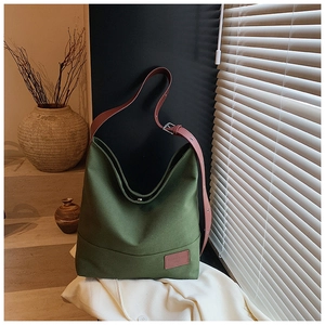 Detail of olive green canvas tote bag with brown leather straps in natural sunlight