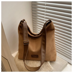 Detail of vintage brown suede tote bag featuring a leather brand tag and wide strap